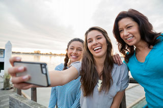 168831425 Three friends laying in the snow taking a selfie with a cell phone